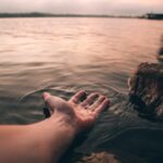 A hand reaching out to the water Description automatically generated